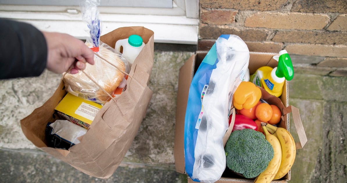 person grabbing shopping bag filled with grocery delivery items 
